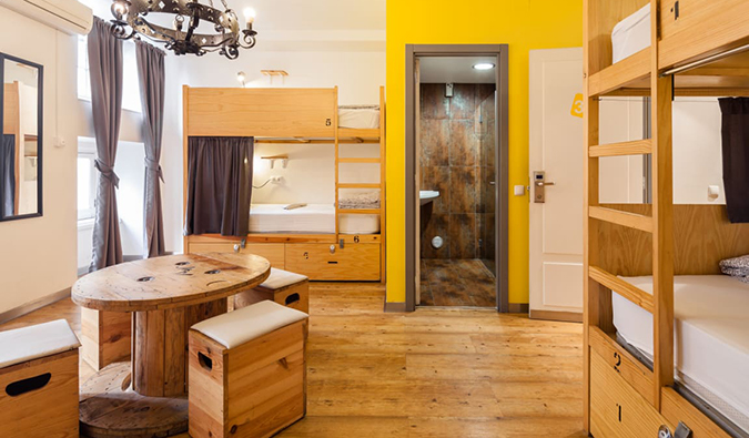 Uma sala comum com beliches de madeira e uma pequena mesa redonda no albergue do sim! Lisboa Hostel