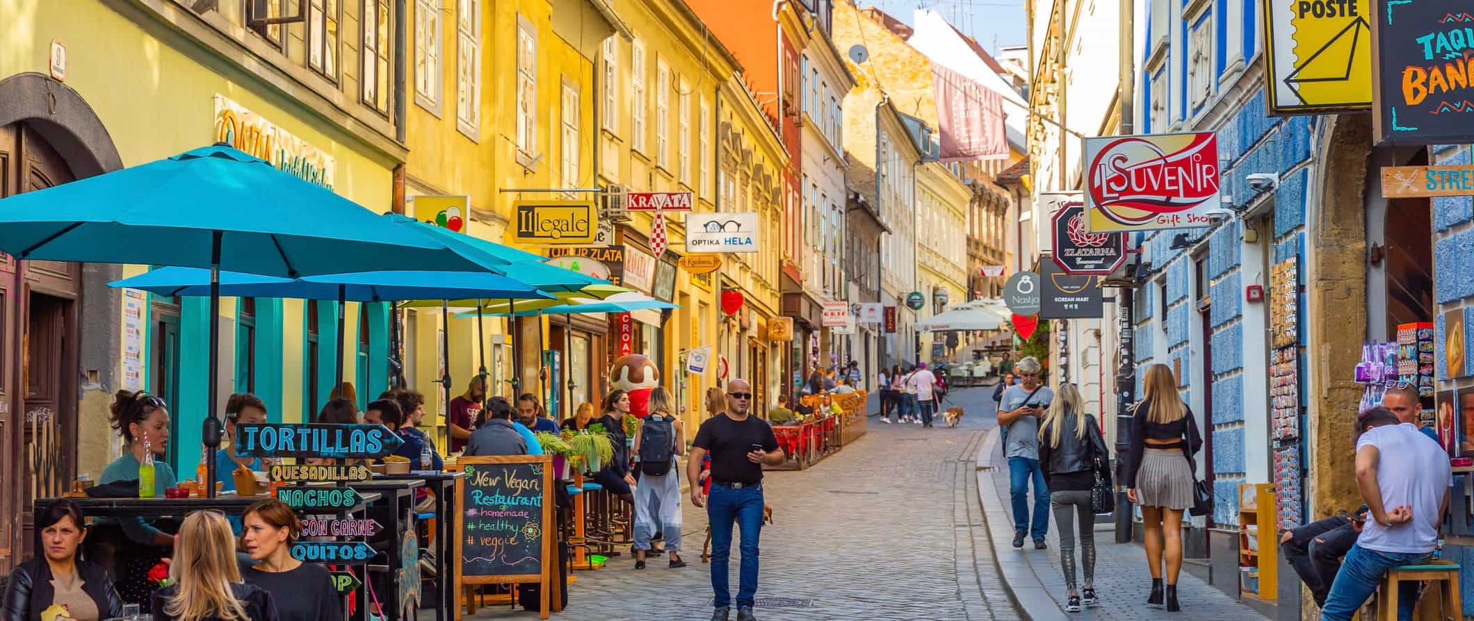 As pessoas andam ao longo de uma rua estreita na antiga cidade de Zagreba, Croácia
