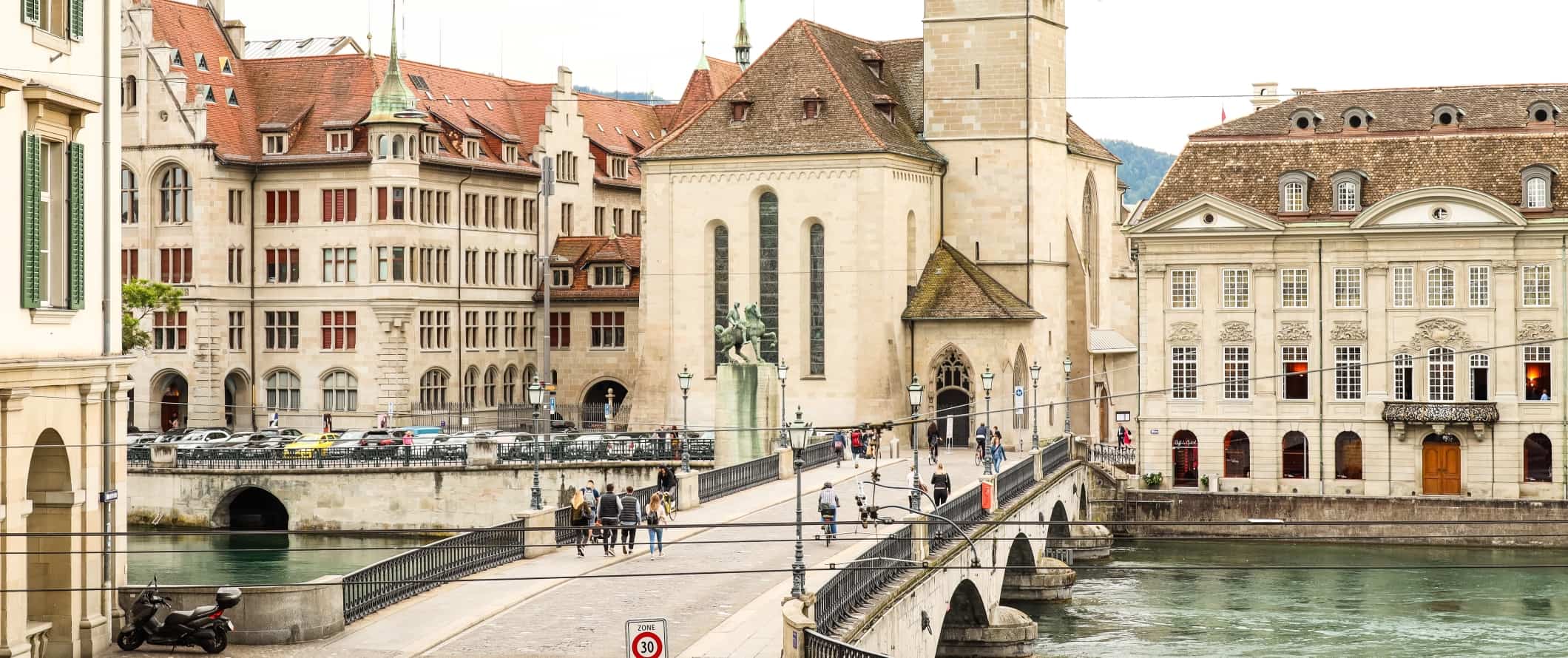 As pessoas andam ao longo da ponte de pedra no centro histórico de Zurique, na Suíça
